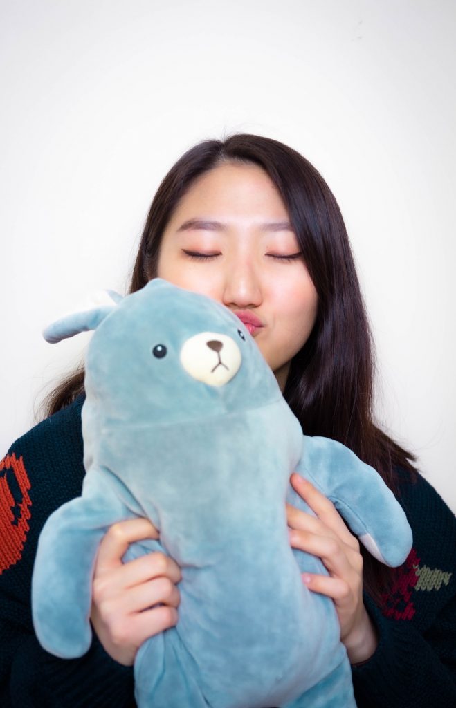A person holds a blue stuffed animal, a great way of embracing your inner child.