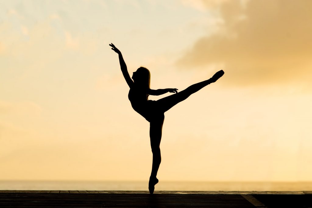 A photo of a person in a ballet pose amidst a sunset. You can use I am statements to uplift yourself.
