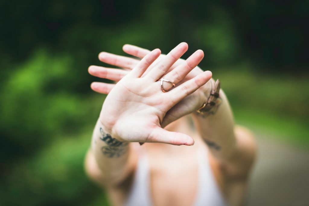 A photo of a person's hands extended out toward the camera, blocking the view of themself. To live for yourself, you've got to stop people pleasing, and put up some healthy boundaries!