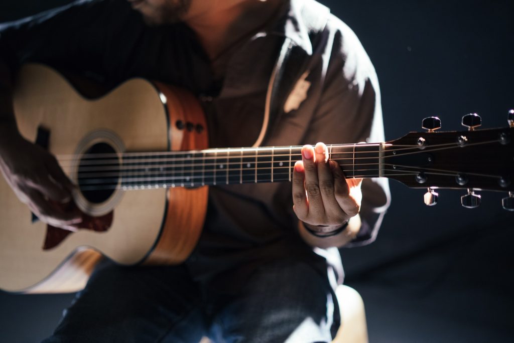 A close up of a person holding an acoustic guitar. If you're looking for new things to try, there are plenty of instruments to choose from!
