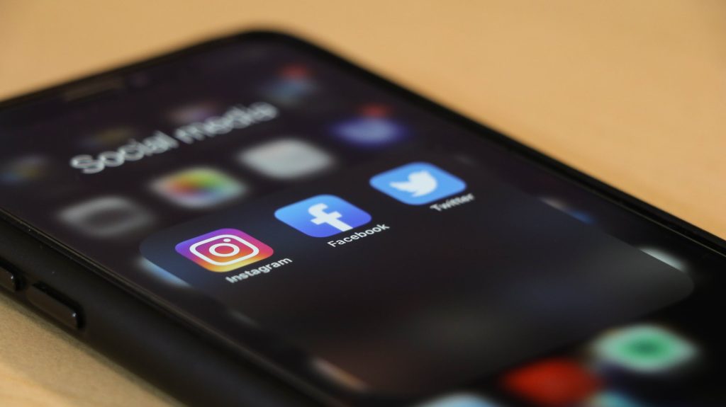 A photo of a smartphone, showing the icons of the apps Instagram, Facebook, and Twitter.