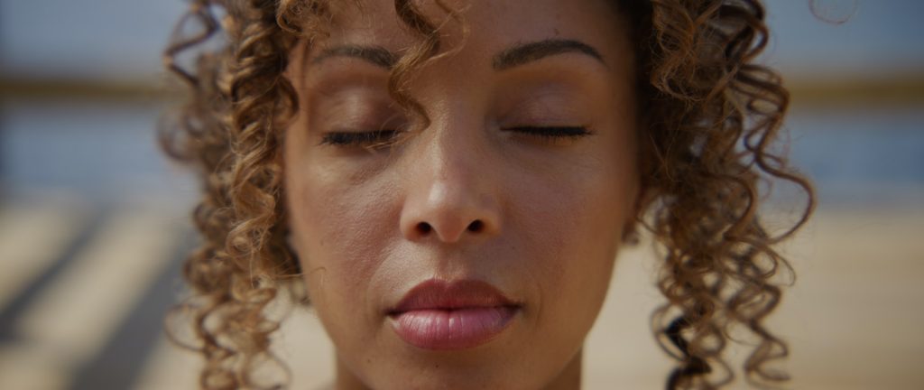 A close up photo of a person's face with their eyes closed, looking peaceful and meditative.