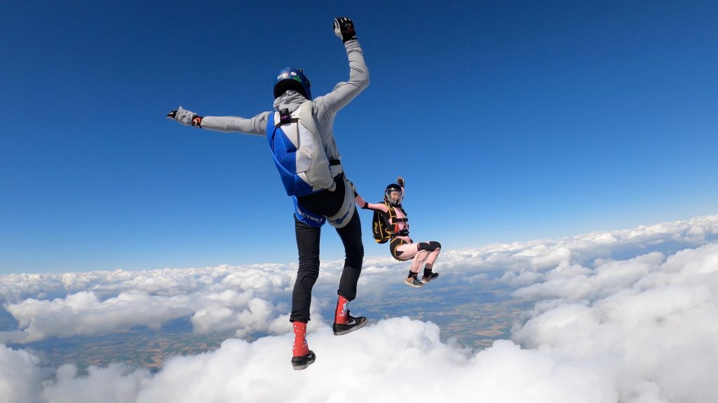 A photo of two people skydiving, looking as though they're walking on the clouds.