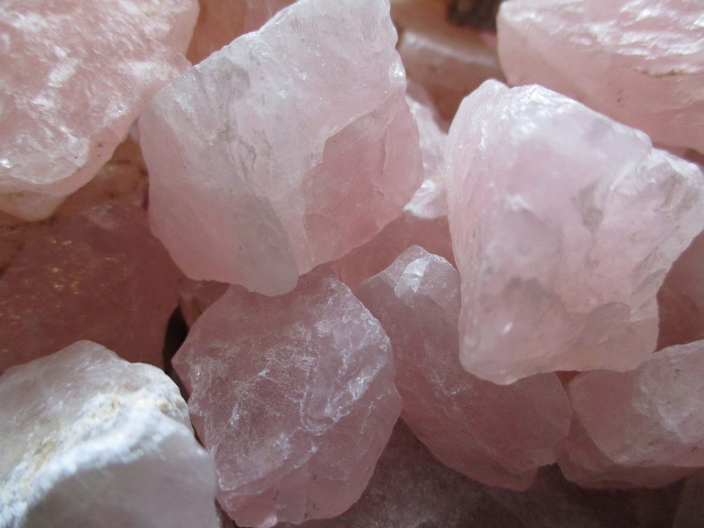 A close up photo of a pile of rose quartz. Rose quartz affirmations can help you focus on being more loving to yourself and others.