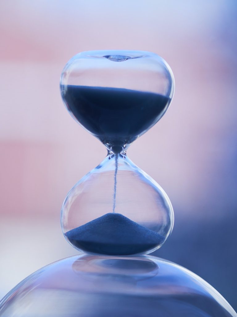 A close up photo of an hourglass, with sand filtering through from the top to the bottom of the glass. Organizing your time is key when organizing your life.