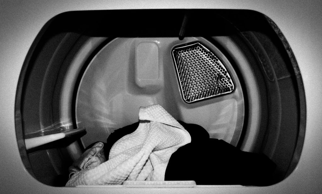 A black and white photo of the inside of a clothes dryer, with some clothes inside.