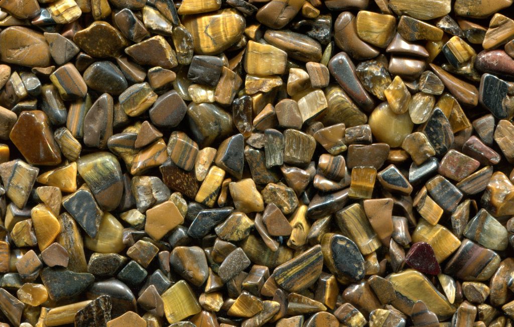 A close up of a pile of tumbled tiger's eye stones. Tiger's eye affirmations can help build self worth and inner strength.