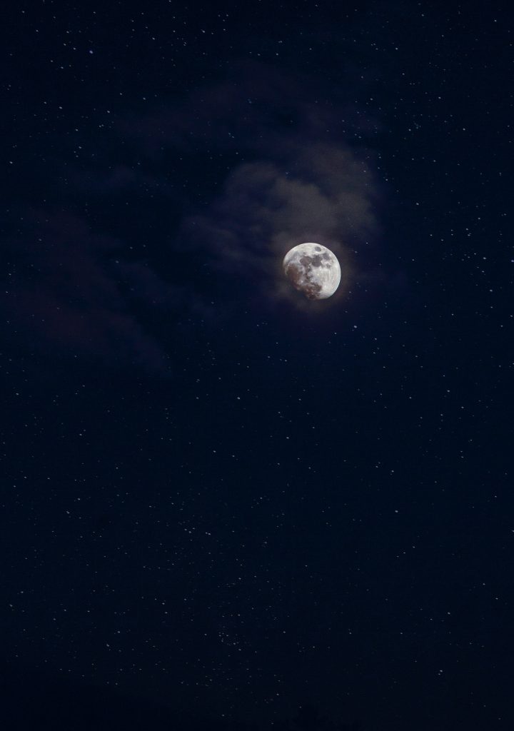 A photo of the moon amidst a dark blue night sky. Saying night time affirmations can be a great way to end your mindful evening routine.