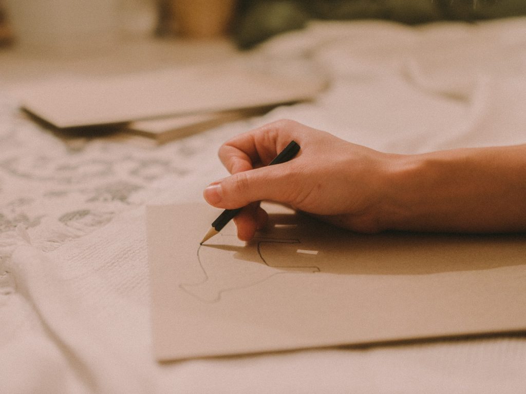 A photo of a hand holding a pencil and sketching something onto paper. If you enjoy your hobby, you should just do it even if you suck at it.