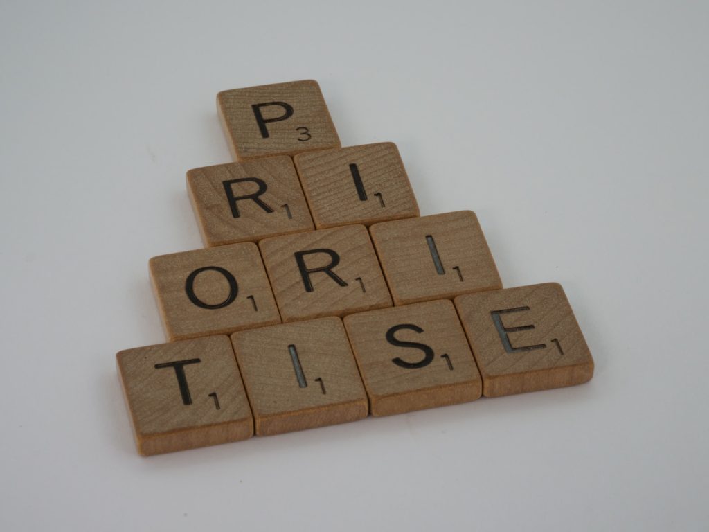 A photo of Scrabble letters arranged in a pyramid to spell the word "prioritise". It's important to have our priorities straight if we want to engage in frugal minimalism.
