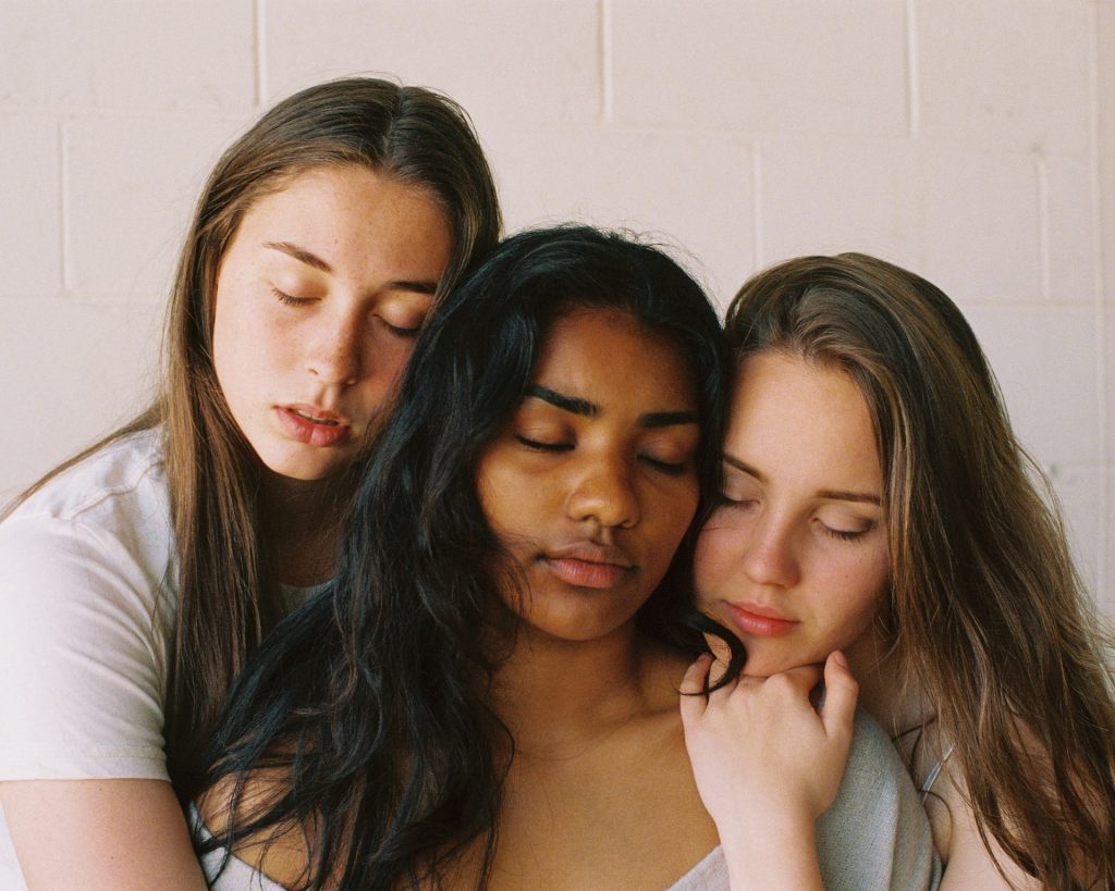 A photo of three friends holding each other close, eyes closed and faces peaceful. Finding like-minded people is essential when you choose to live for yourself.